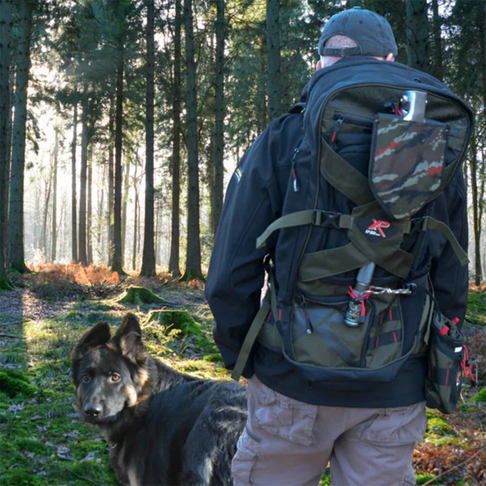 Person with a large backpack and a dog in a forest